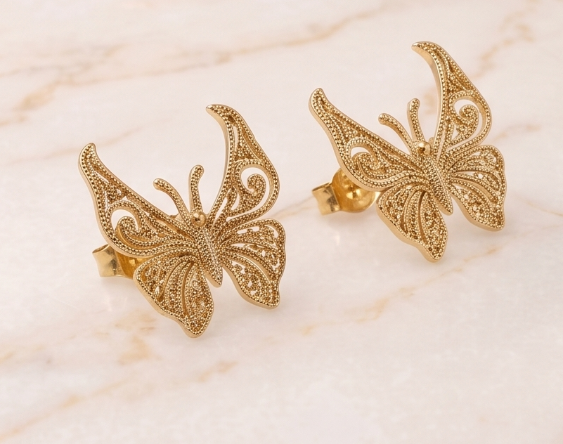 Gold butterfly earrings on a marble surface