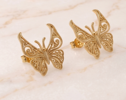 Gold butterfly earrings on a marble surface