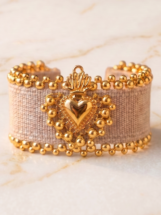 Gold beaded bracelet with heart design on a marble surface