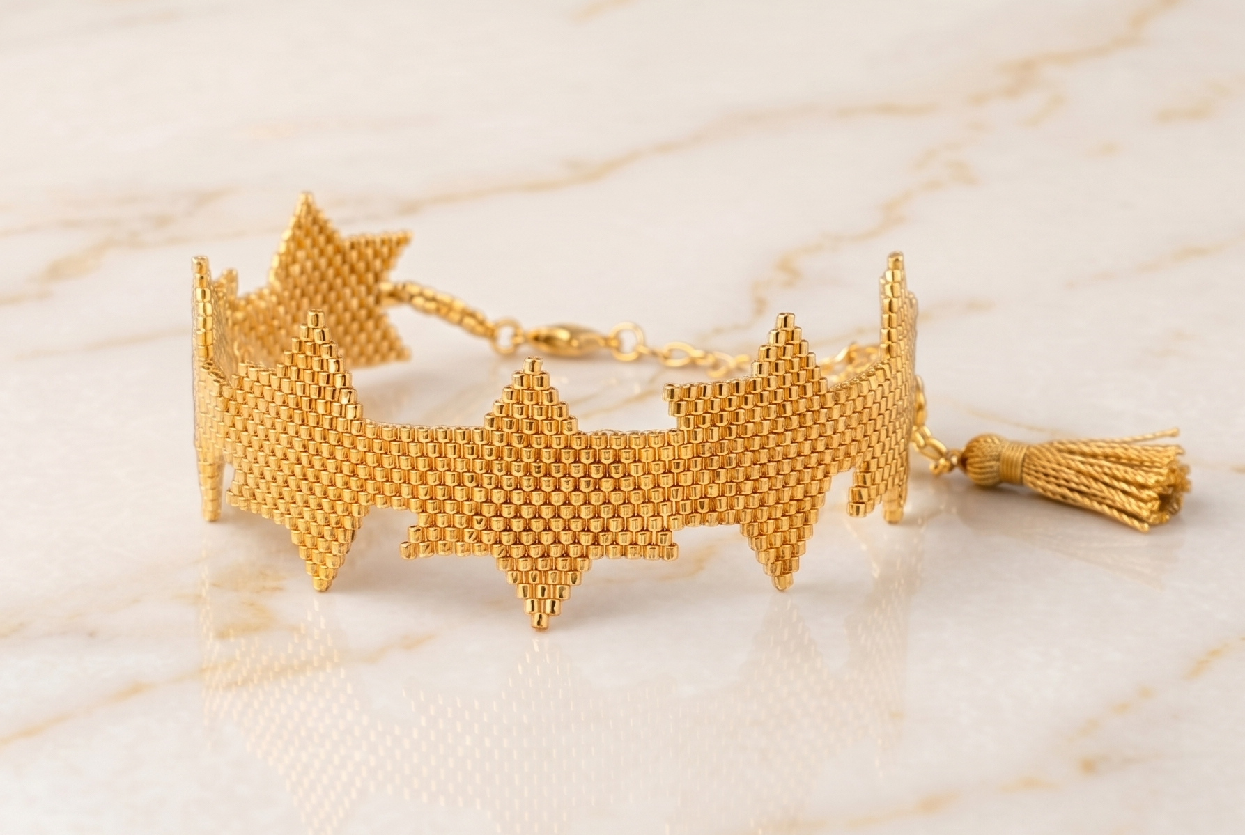 Gold bracelet with tassel on a marble surface