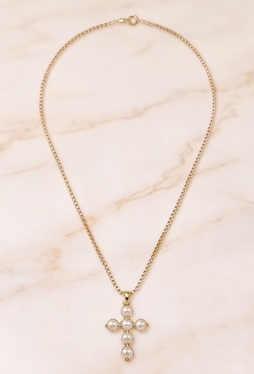 Gold necklace with a cross pendant on a marble surface