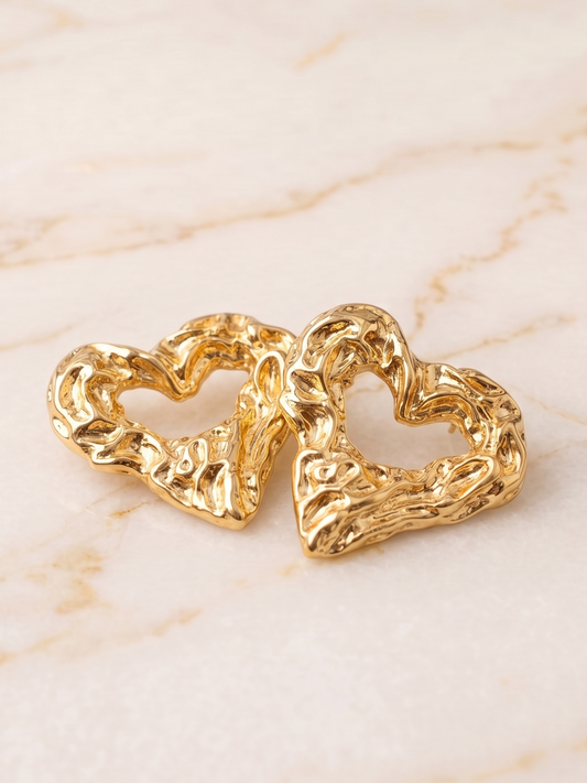 Gold heart-shaped earrings on a marble surface
