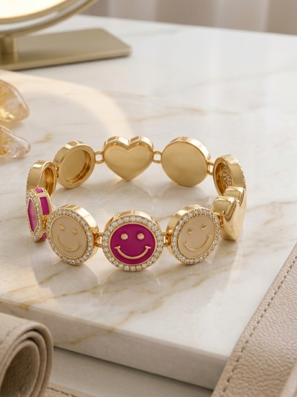 Gold bracelet with heart and smiley face charms on a marble surface with a mirror in the background.