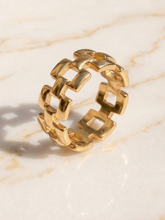 Gold chain-link ring on a light marble background